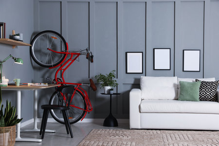 Red bicycle and stylish furniture near gray wall indoorsの写真素材