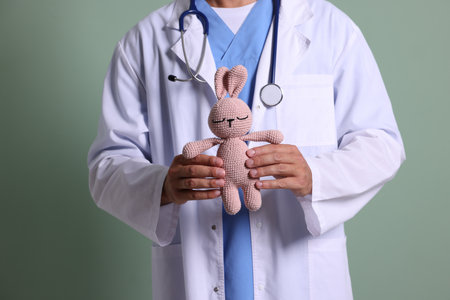 Pediatrician with toy bunny on green background, closeupの写真素材