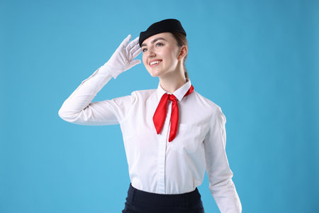 Charming stewardess in uniform on light blue backgroundの写真素材