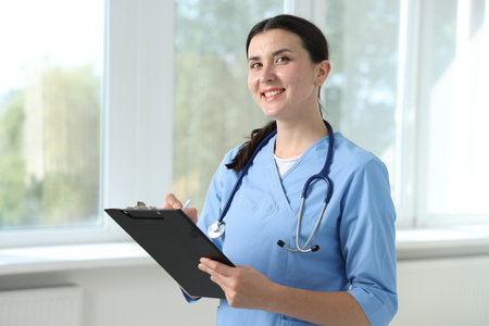 Nurse with clipboard taking notes near window in clinic