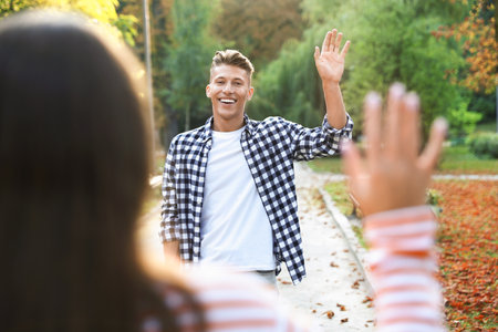 Person waving goodbye to a friend in park, selective focusの写真素材