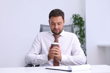 Air conditioning. Man with cup of hot drink suffering from cold temperature at workplace in office
