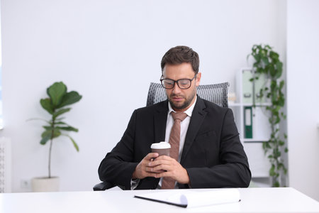 Air conditioning. Man with cup of hot drink suffering from cold temperature at workplace in officeの写真素材