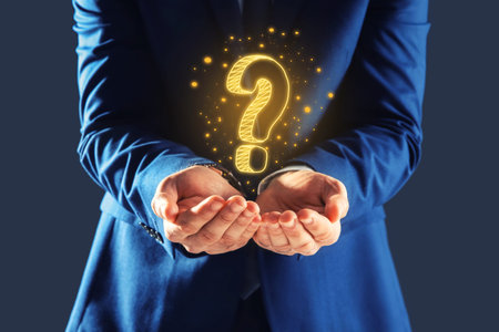 Businessman holding question mark against dark gray background, closeup