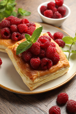 Yummy puff pastries with raspberries and mint on wooden table, closeupの写真素材