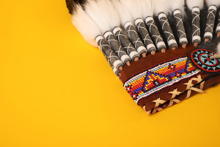 Traditional warbonnet (Native American chief headdress) on yellow background, closeup