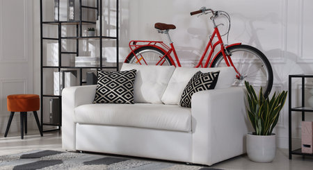 Red bicycle, sofa and houseplant in roomの写真素材