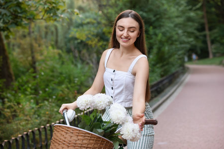 Woman riding bicycle with flowers in basket outdoorsの写真素材