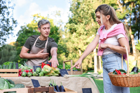 Woman choosing fresh vegetables from stall at farmer's marketの写真素材