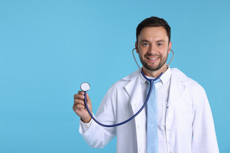 Pediatrician with stethoscope on light blue background. Space for textの写真素材