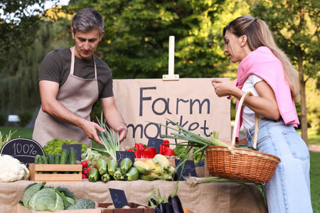 Woman choosing fresh vegetables from stall at farmer's market