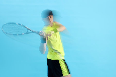 Man with racket playing tennis on light blue background, motion blur effectの写真素材