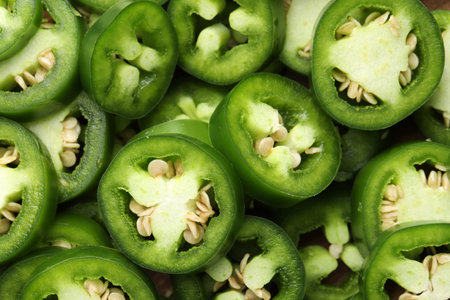 Fresh green jalapeno pepper slices as background, closeup