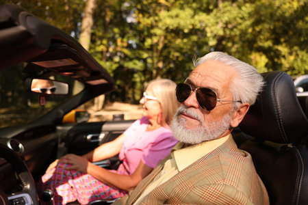 Senior couple enjoying cabriolet ride in city, selective focusの写真素材