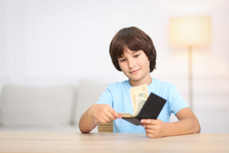 Boy with pocket money at wooden table indoors. Space for textの写真素材