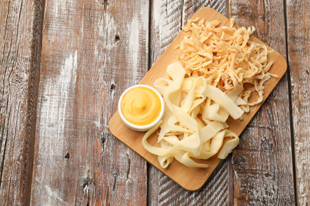 Dried shredded squid, shavings and sauce on color wooden table, top view. Space for text