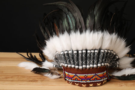 Traditional warbonnet (Native American chief headdress) on wooden table against black background