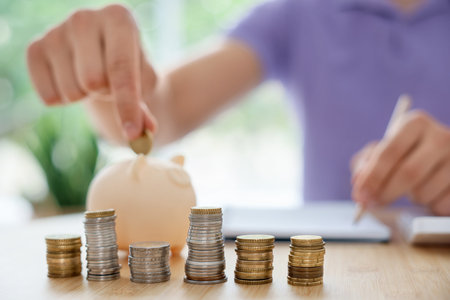 Man putting coin into piggy bank at wooden table indoors, selective focus
