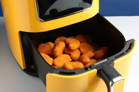 Air fryer with chicken nuggets on white table, closeupの写真素材