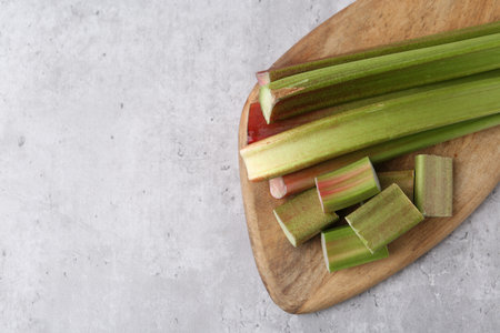 Fresh ripe rhubarb on light gray table, top view. Space for text