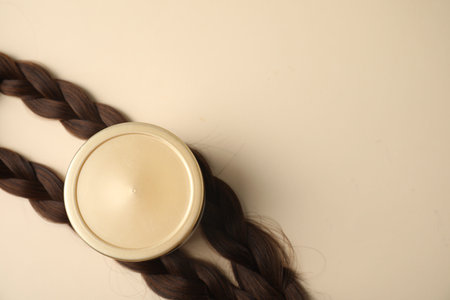 Braided hair locks and cosmetic product on beige background, flat lay. Space for textの写真素材