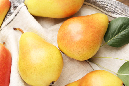 Many fresh pears and napkin on table, top view