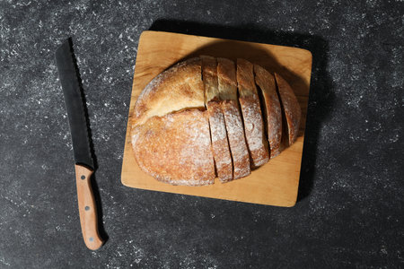 Fresh cut bread and knife on gray textured table, top view