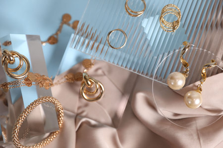 Stylish presentation of beautiful gold jewelry on light blue background, flat layの写真素材