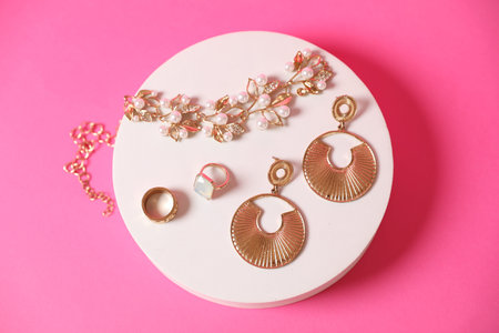 Stylish presentation of beautiful gold jewelry on pink background, top view