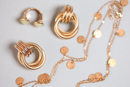 Stylish presentation of gold jewelry on light background, flat layの写真素材
