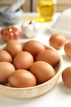 Raw eggs in bowl on white table, closeupの写真素材