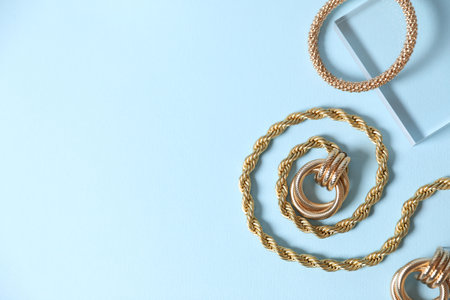 Beautiful gold jewelry on light blue background, flat lay. Space for textの写真素材