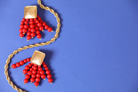 Gold jewelry on blue background, flat lay. Space for textの写真素材