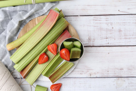 Rhubarb stalks and strawberries on white wooden table, flat lay. Space for textの写真素材