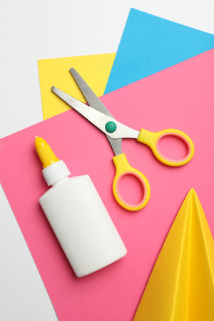 Glue, scissors, handmade plane and color paper on white background, flat layの写真素材