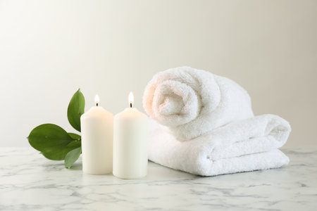 Burning candles, towels and leaves on white marble table, closeupの写真素材
