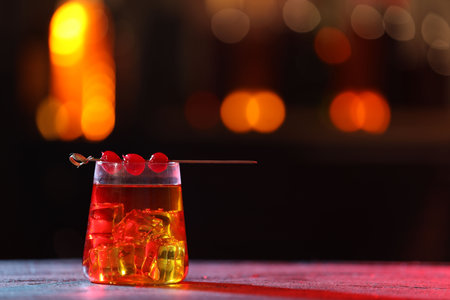 Glass of alcoholic cocktail with garnish on table against blurred background, space for text. Bokeh effectの写真素材