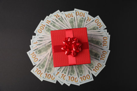 Gift box and dollar banknotes on black background, top viewの写真素材