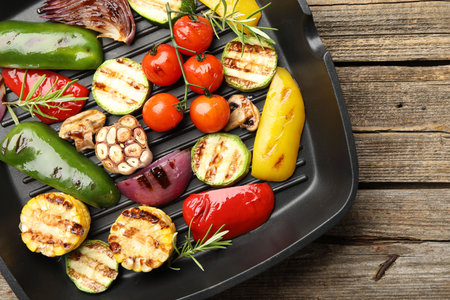 Pan with grilled vegetables and spices on wooden table, top viewの写真素材