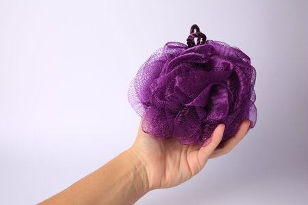 Woman holding purple mesh sponge on white background, closeup. Space for text