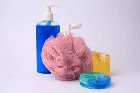 Pink shower puff and cosmetic products on white background