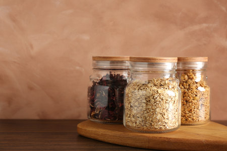 Glass jars with different products on wooden table. Space for textの写真素材