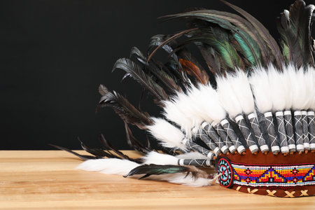 Traditional warbonnet (Native American chief headdress) on wooden table against black background, closeupの写真素材
