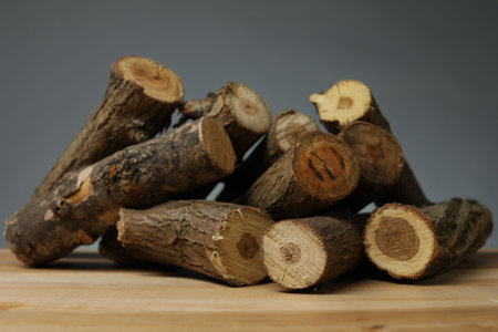 Pile of cut firewood on wooden table against gray background, closeupの写真素材