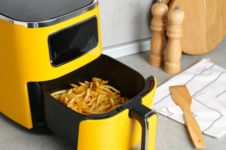 Modern air fryer with cooked French fries on gray background, closeupの写真素材