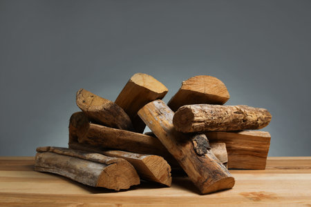 Pile of cut firewood on wooden table against gray background