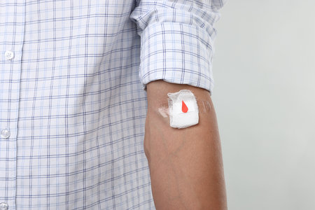 Blood donation. Man with bandage on arm against light background, closeupの写真素材