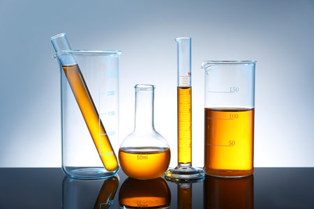 Different glassware with liquid on mirror surface against gray backgroundの写真素材