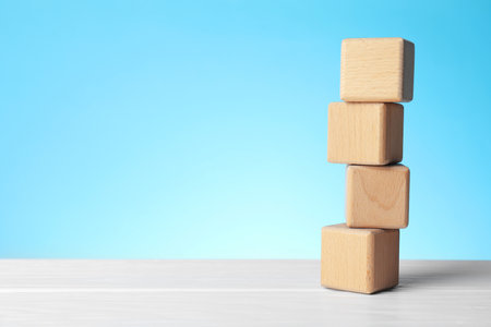 Blank wooden cubes on white table against light blue background, space for textの写真素材