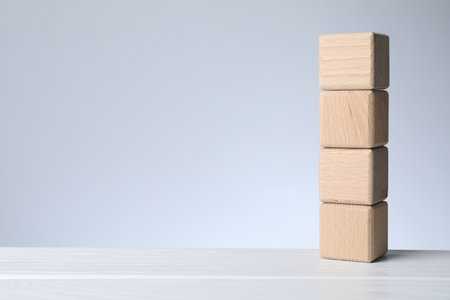 Blank cubes on white wooden table against light gray background, space for textの写真素材